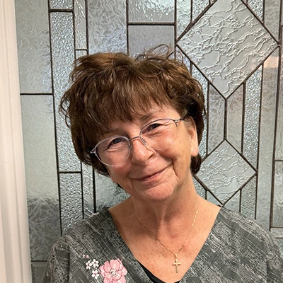 Dental Hygienist Andrea Smiling In Front Of Glass Door