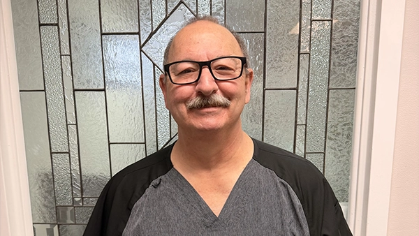 Dentist David Vaughan Smiling In Front Of Glass Door