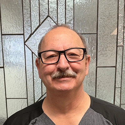 Dentist David Vaughan Smiling In Front Of Glass