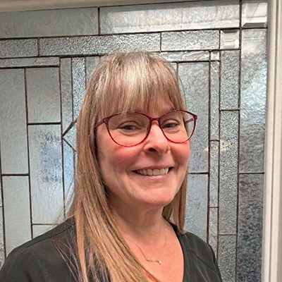 Office Manager Erica Smiling In Front Of Glass Door