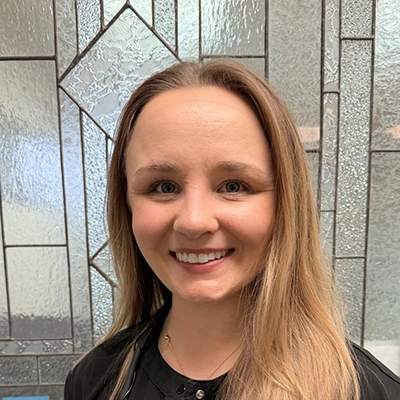 Dental Assistant Kayla Smiling In Front Of Glass Door