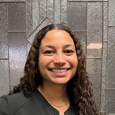 Dental Assistant Larissa Smiling In Front Of Glass Door